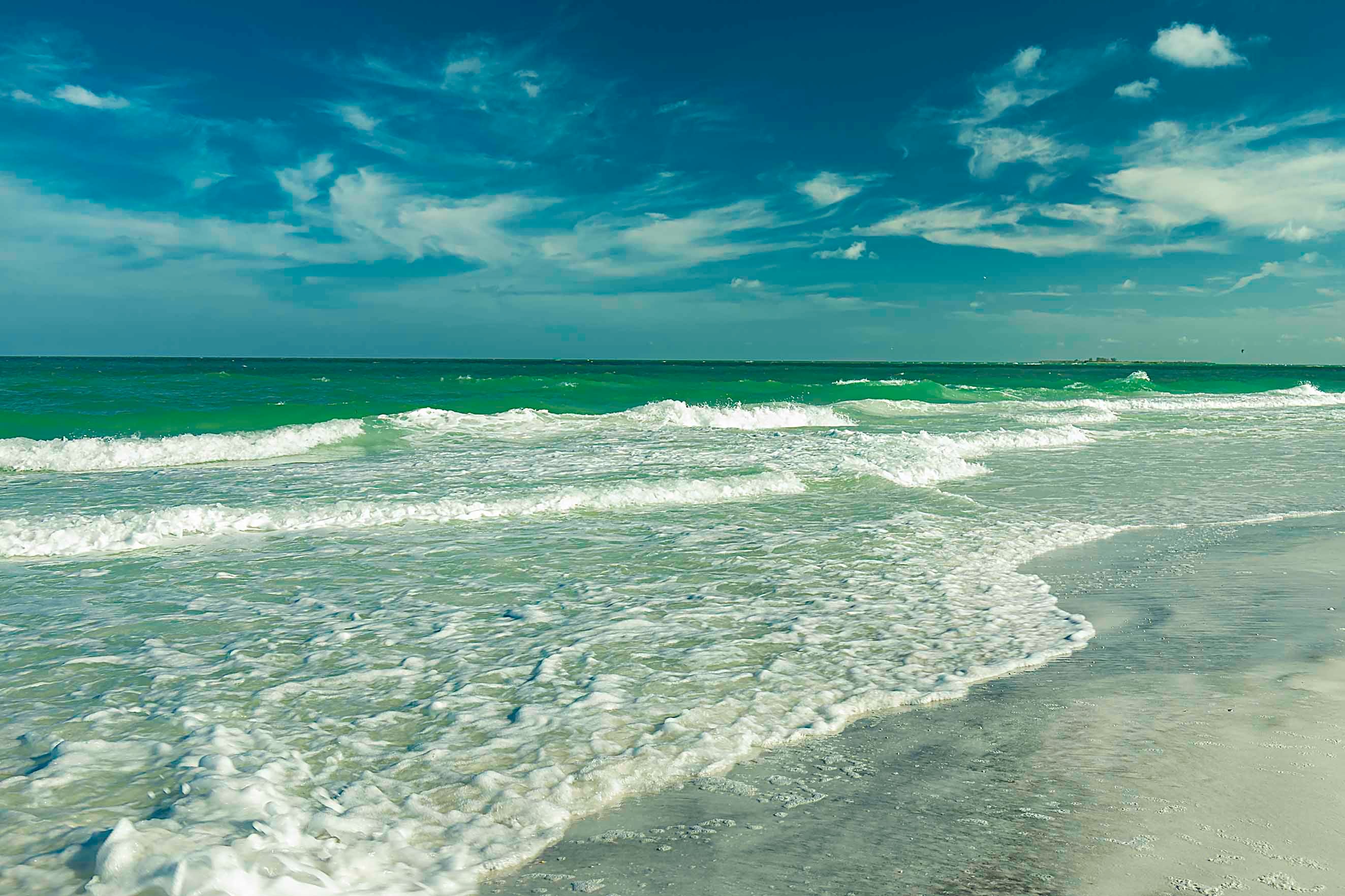 Brilliant emerald Gulf waves rolling in under a vivid blue sky