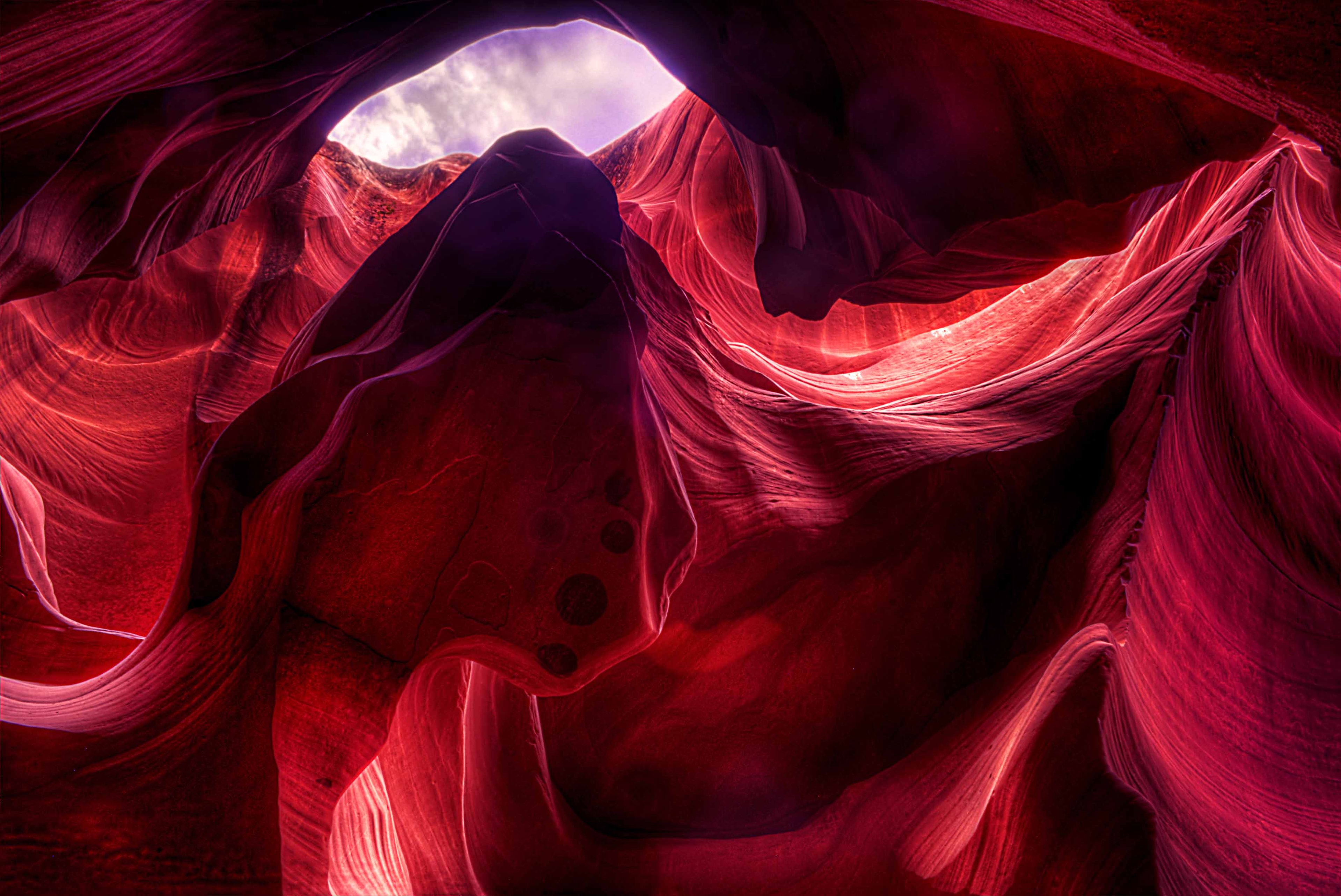 A shaft of light descending through the narrow opening of Antelope Canyon, illuminating swirling sandstone walls in shades of orange and copper