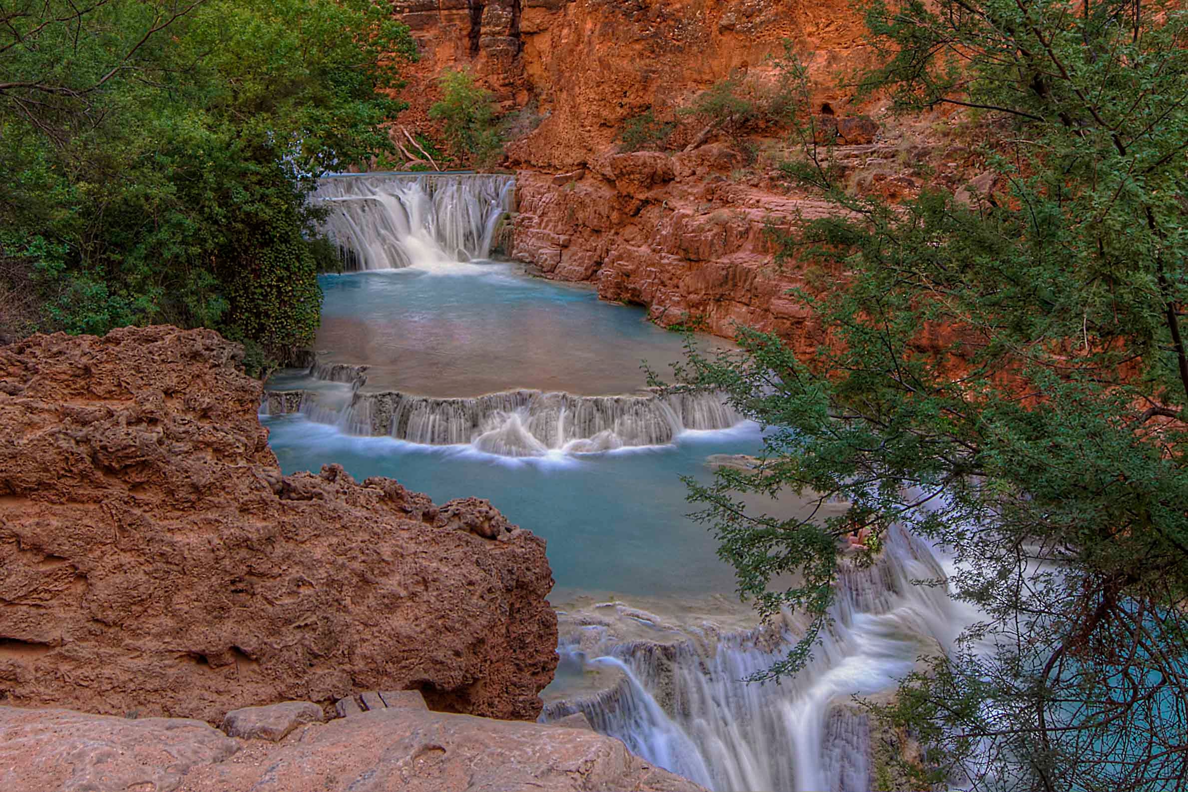 Beaver Falls Arizona, a series of turquoise cascades tumbling over red travertine ledges into glowing pools