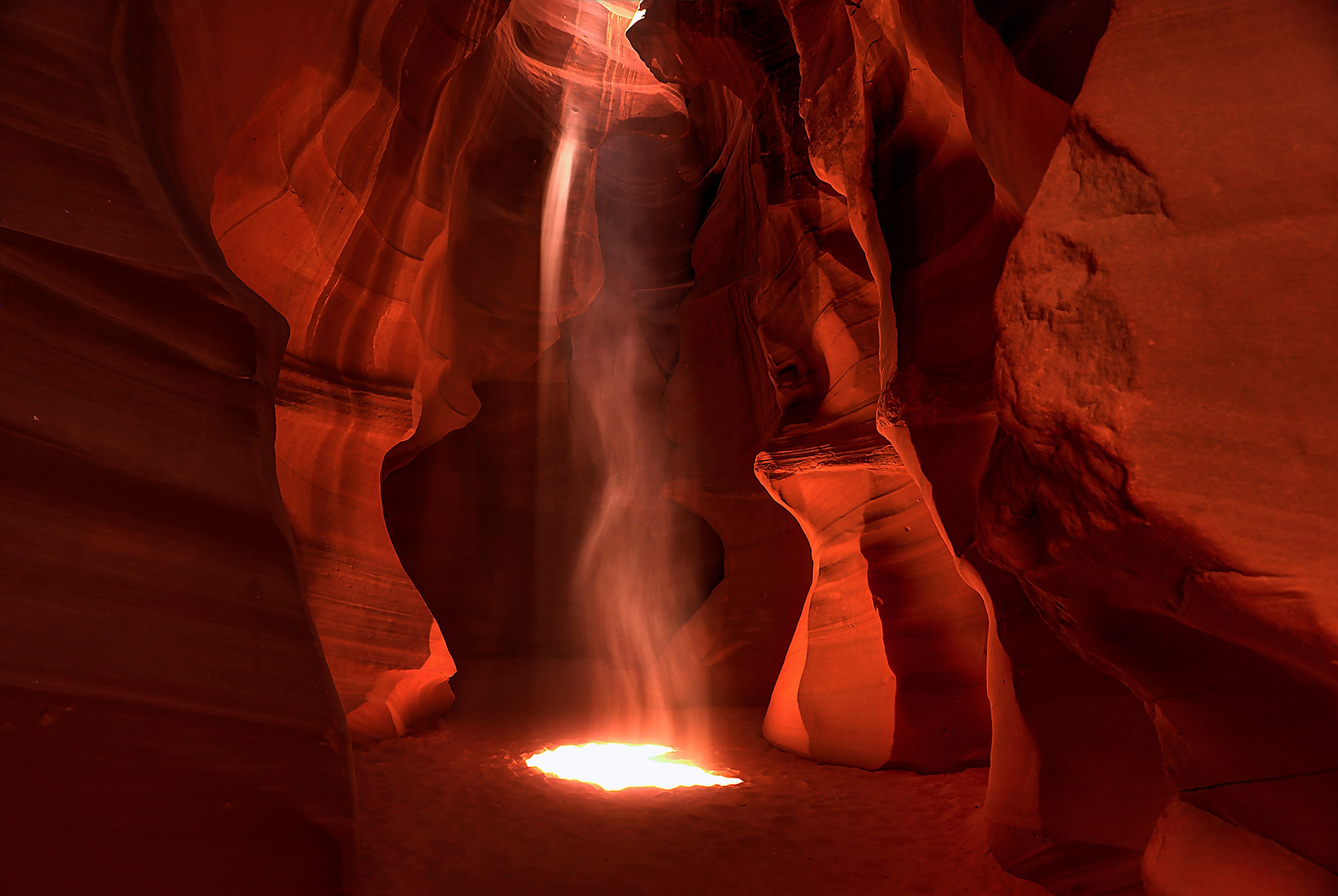 Towering red sandstone walls of Upper Antelope Canyon with dramatic light beams piercing the narrow opening far above