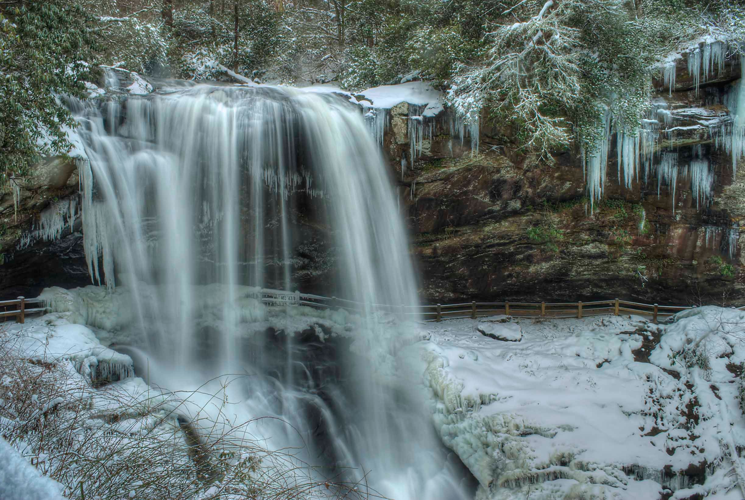 Dry Falls roaring over a wide ledge surrounded by massive icicles and snow-covered rocks