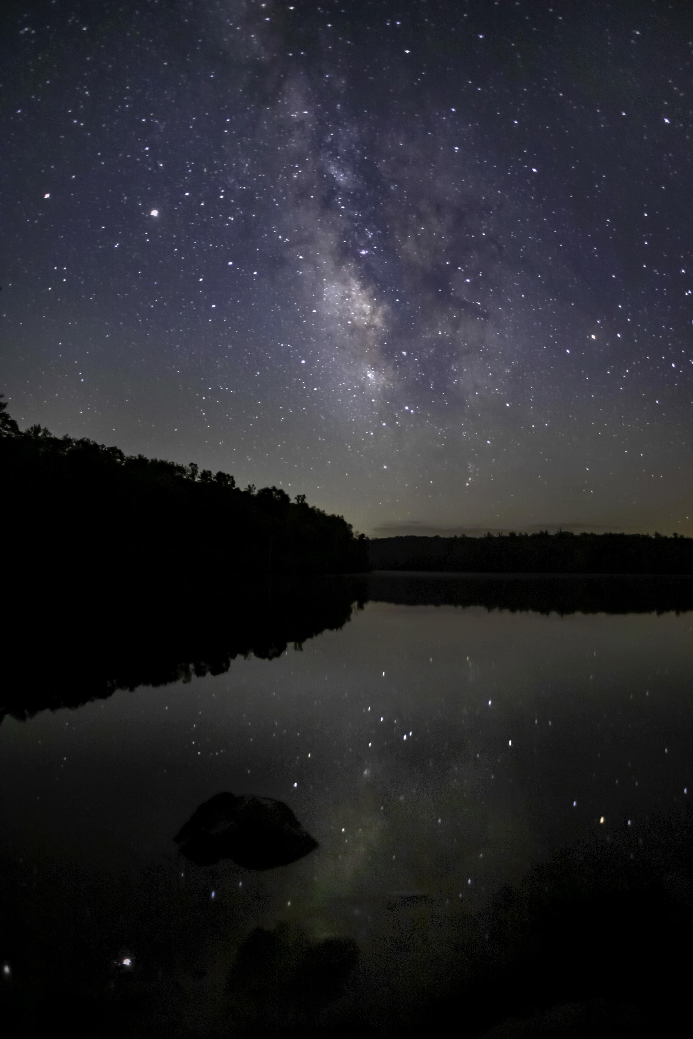 Milky Way reflected in the still waters of Price Lake with a lone boulder