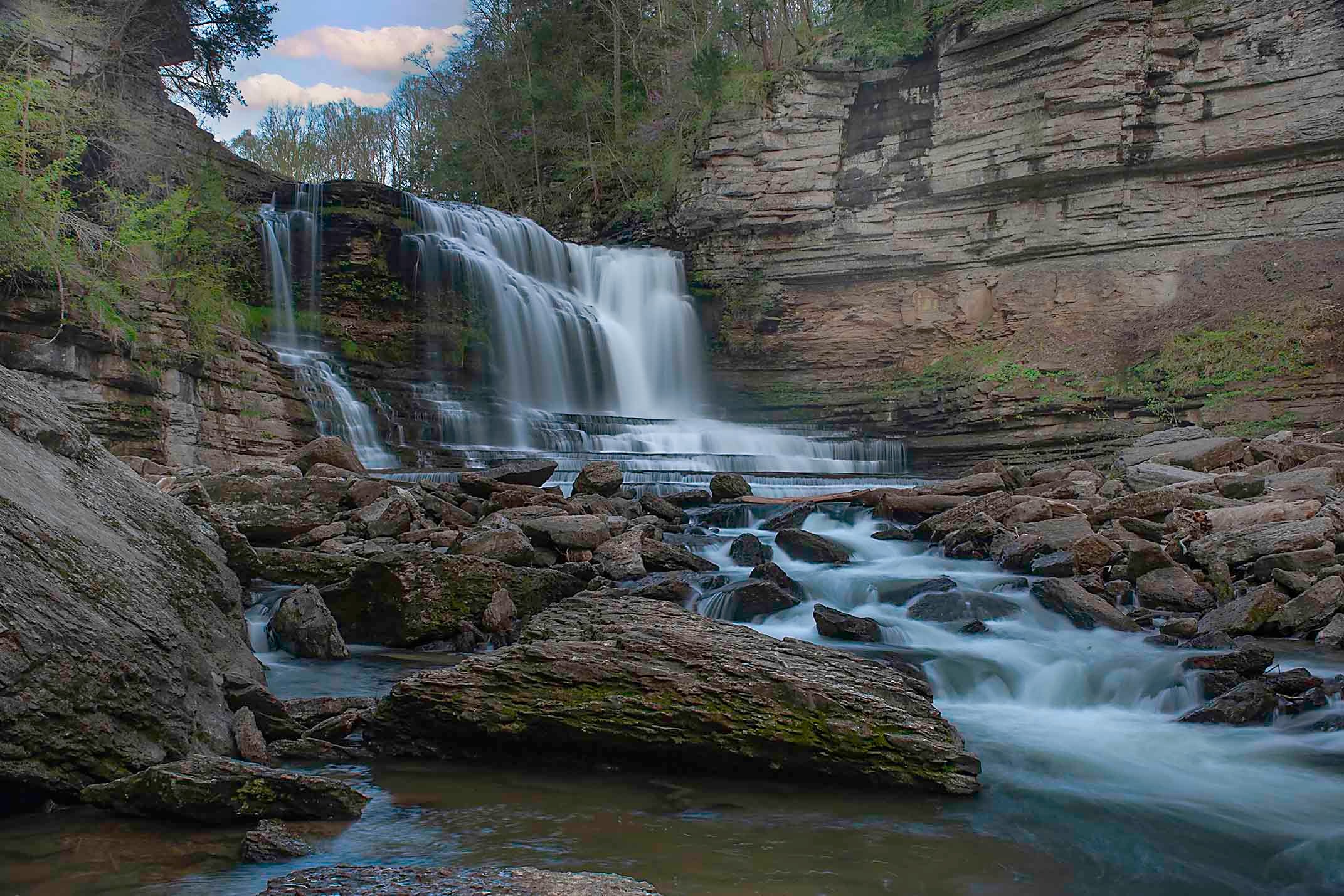 Cumming Falls cascading in wide silky tiers over layered limestone ledges into a rocky gorge