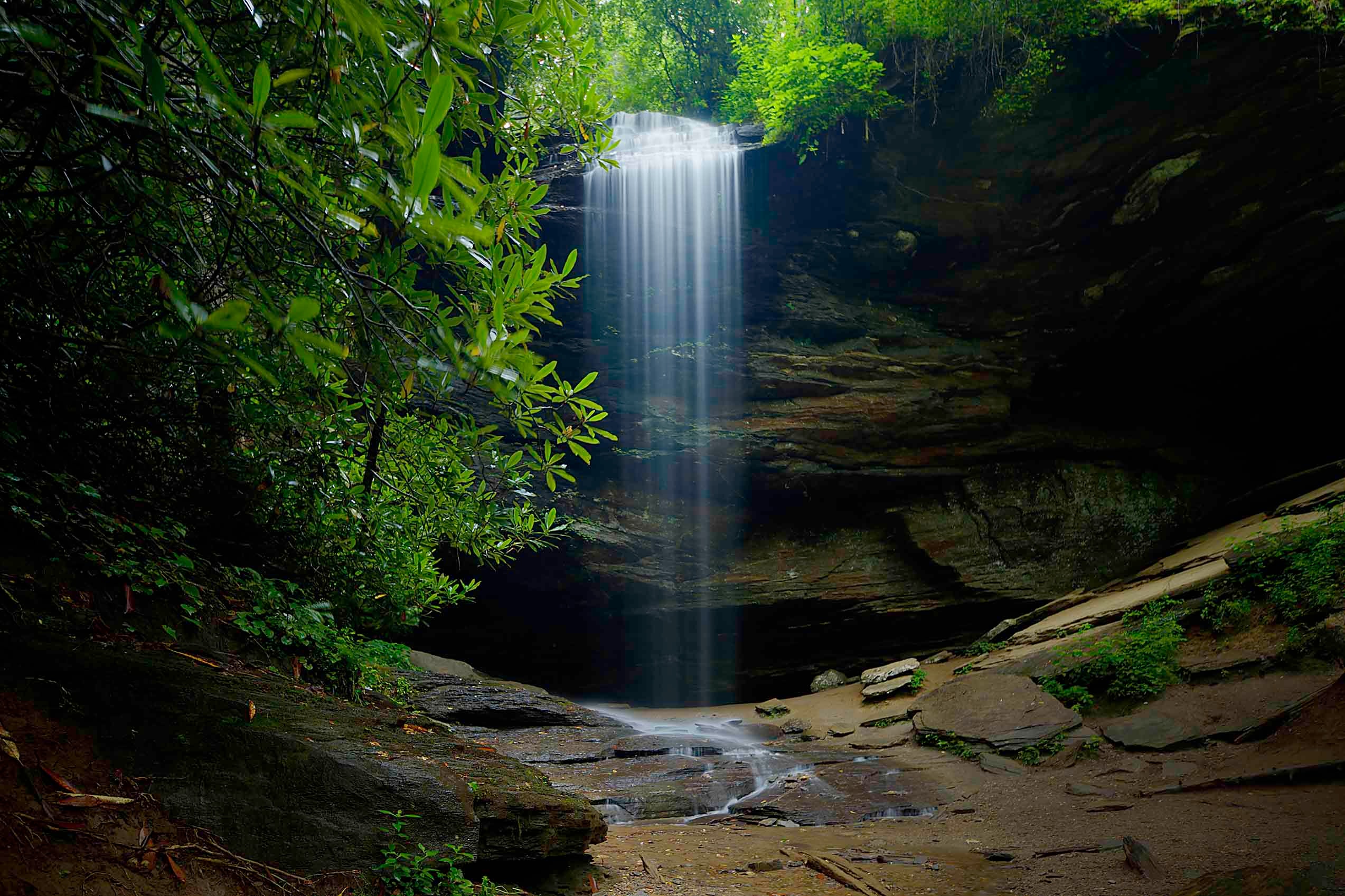 Moore Cove Falls dropping in a luminous curtain over dark sandstone into a shallow pool